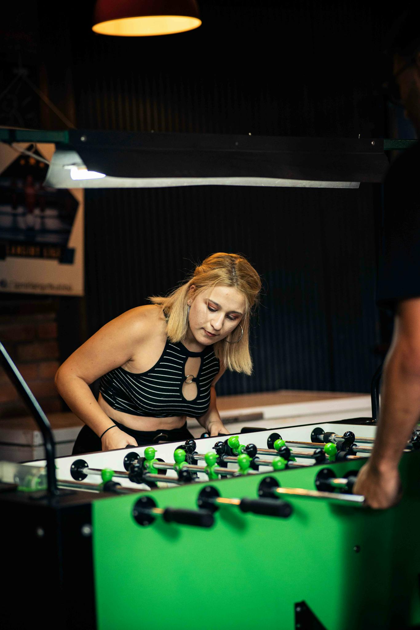A young woman plays foosball at an indoor leisure facility, focused and enjoying her time.