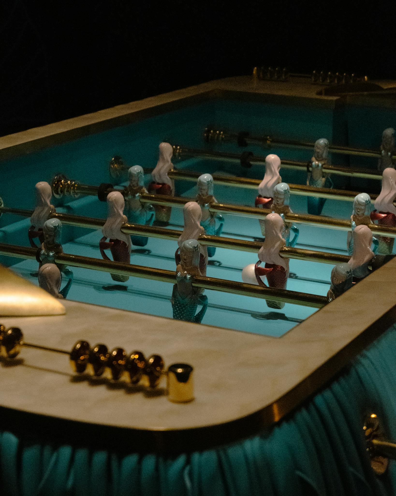 Mermaid foosball table with ornate design, captured indoors at night.