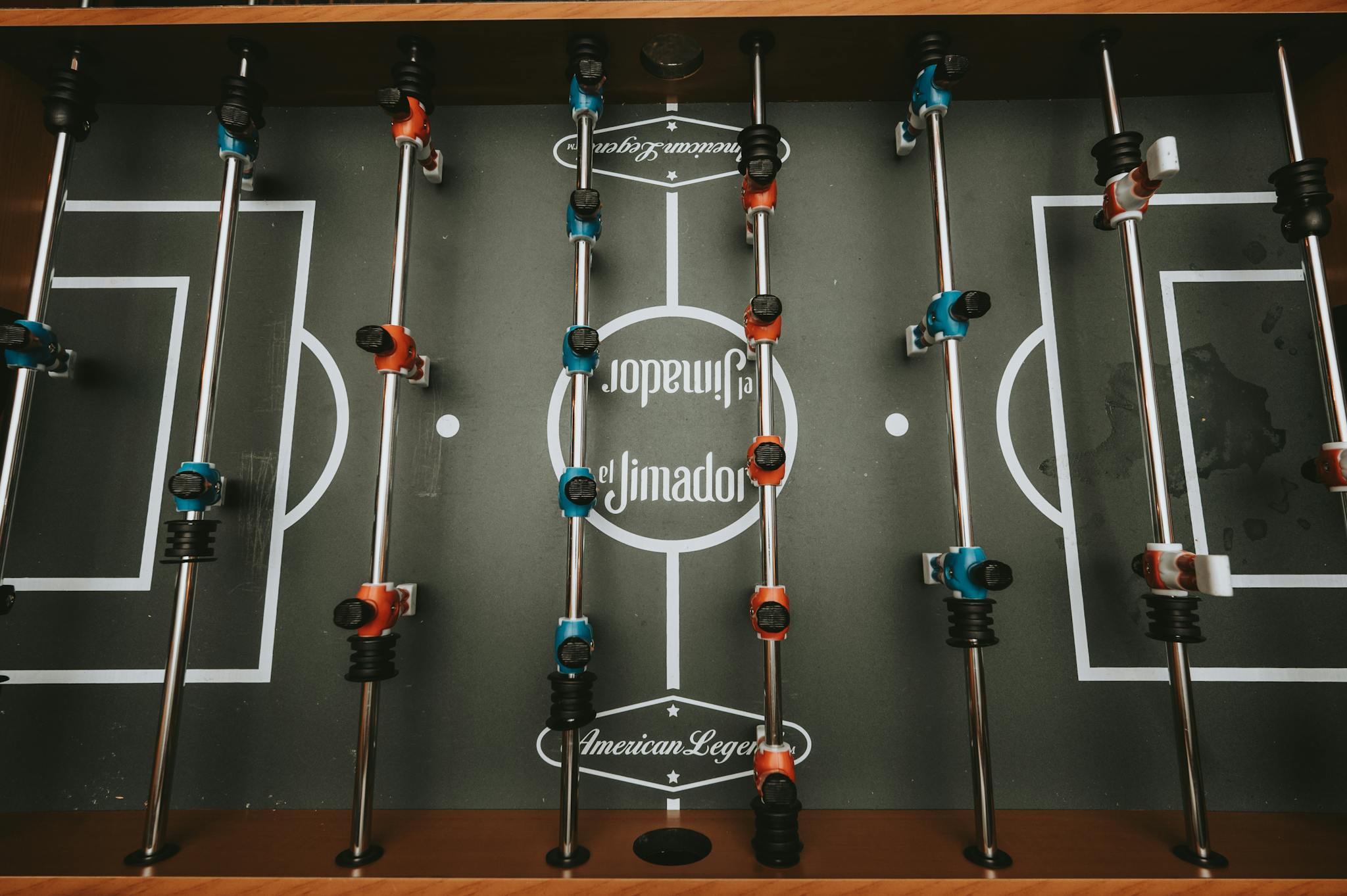 Top view of a foosball table with blue and red players, ready for play.