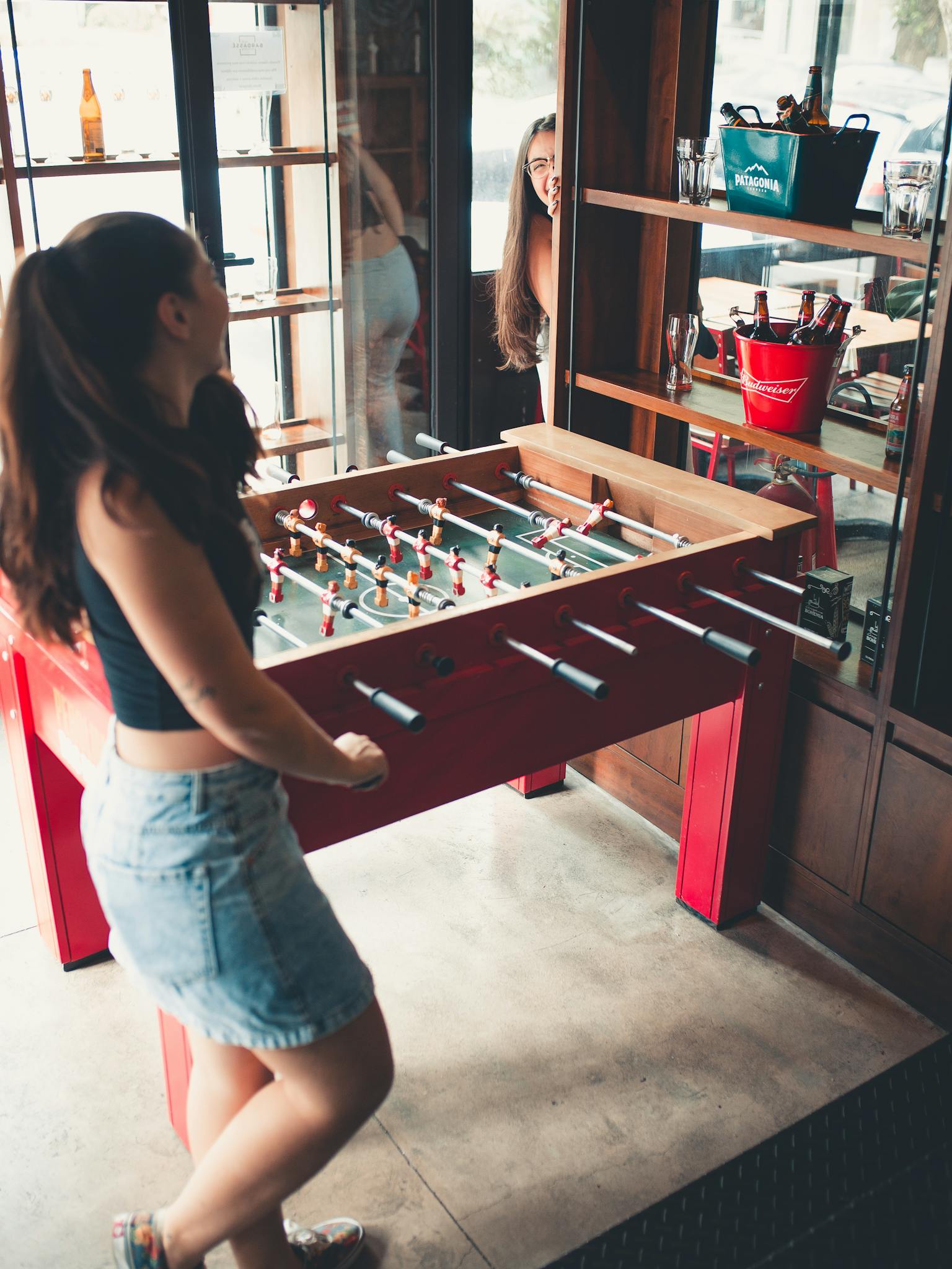 Two young women having fun playing foosball indoors, captured in a lively moment.